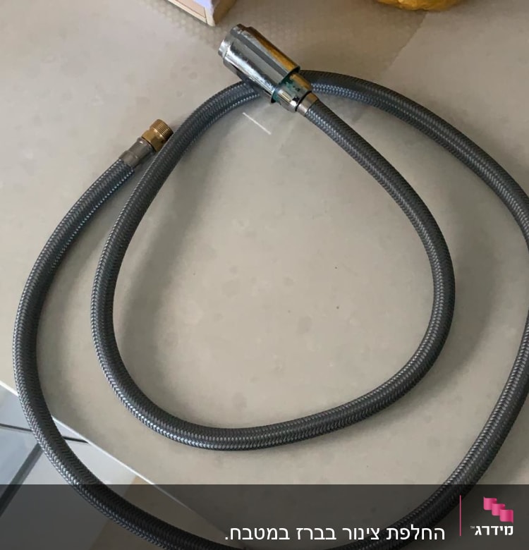 צינור גמיש עם חיבורים מתכתיים על שולחן
